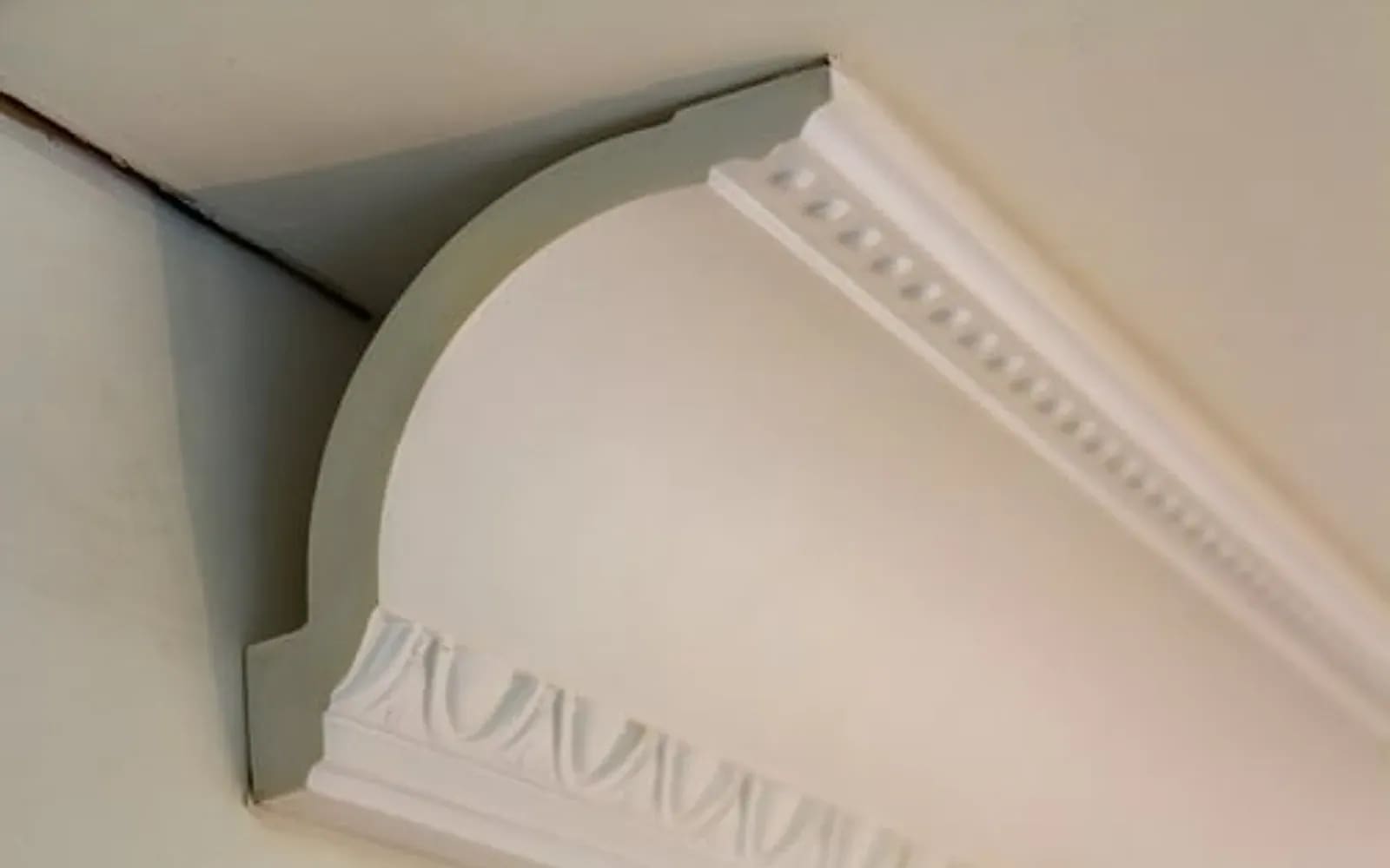 Ornate crown molding profile detail with dentil course installed at a ceiling line