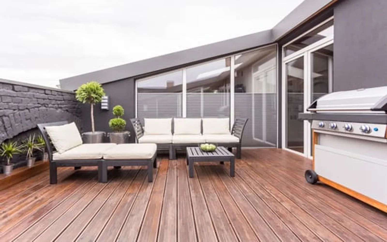 Finished dark hardwood deck with outdoor lounge furniture beside a home exterior