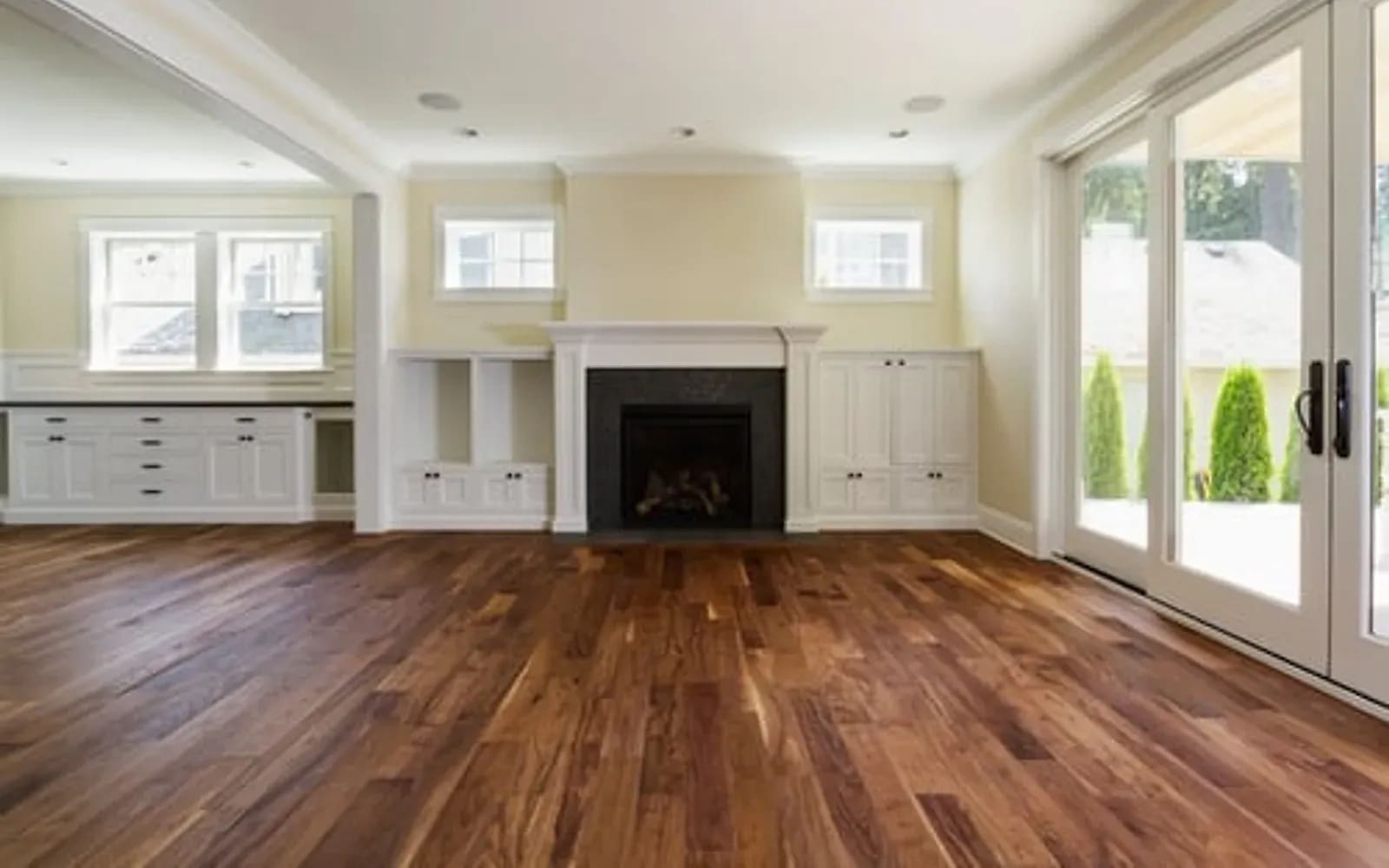 Refinished dark hardwood flooring in a bright open living room with white trim