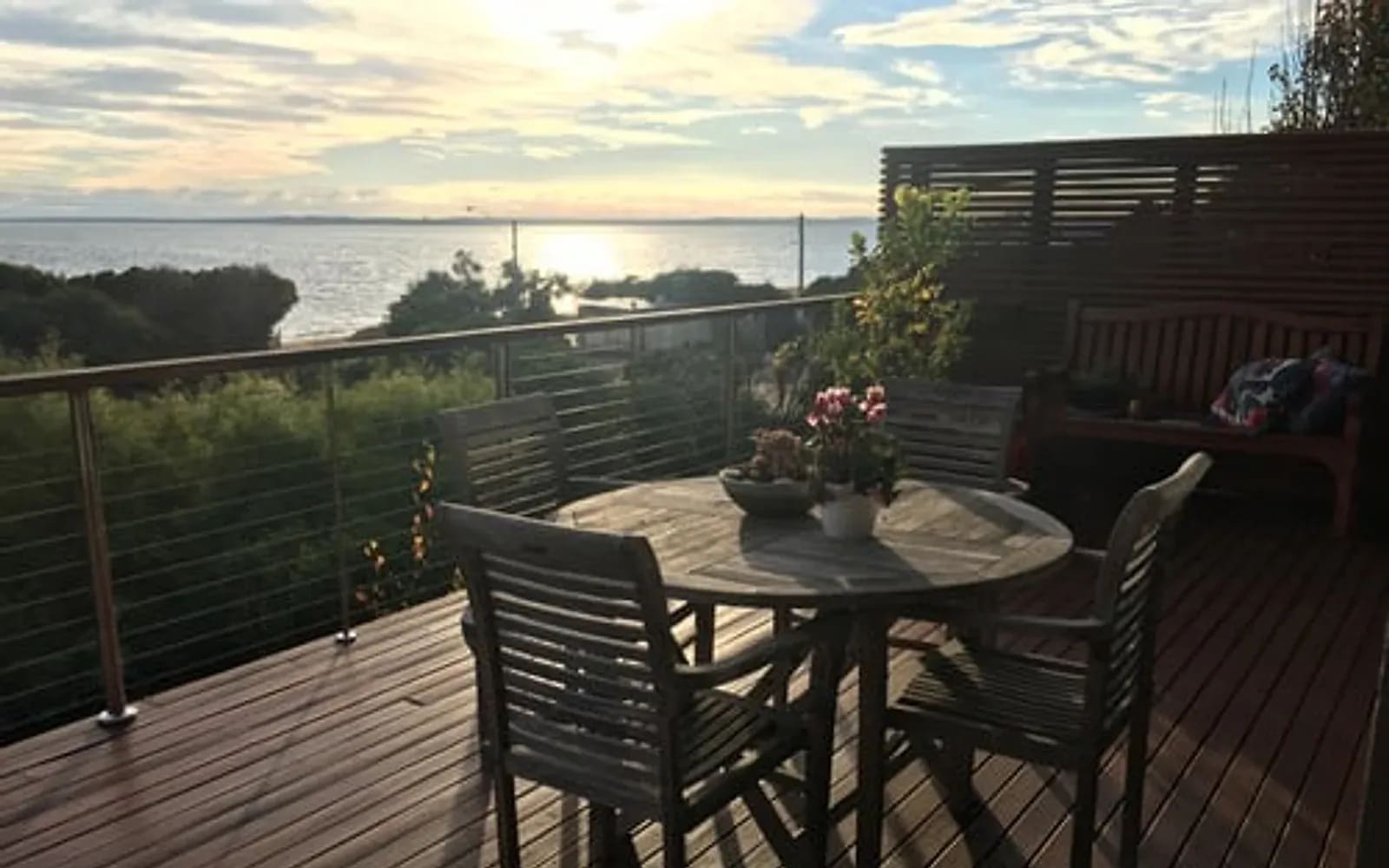 Finished waterfront hardwood deck with dining furniture at dusk on the East End