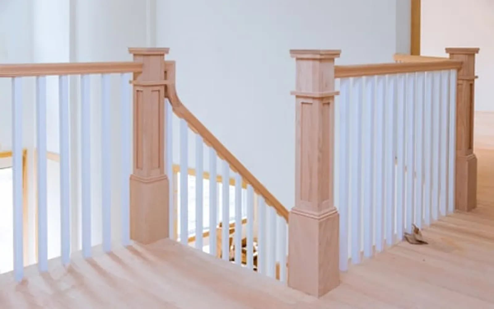 Newly installed hardwood staircase with square newel posts, handrail and white balusters